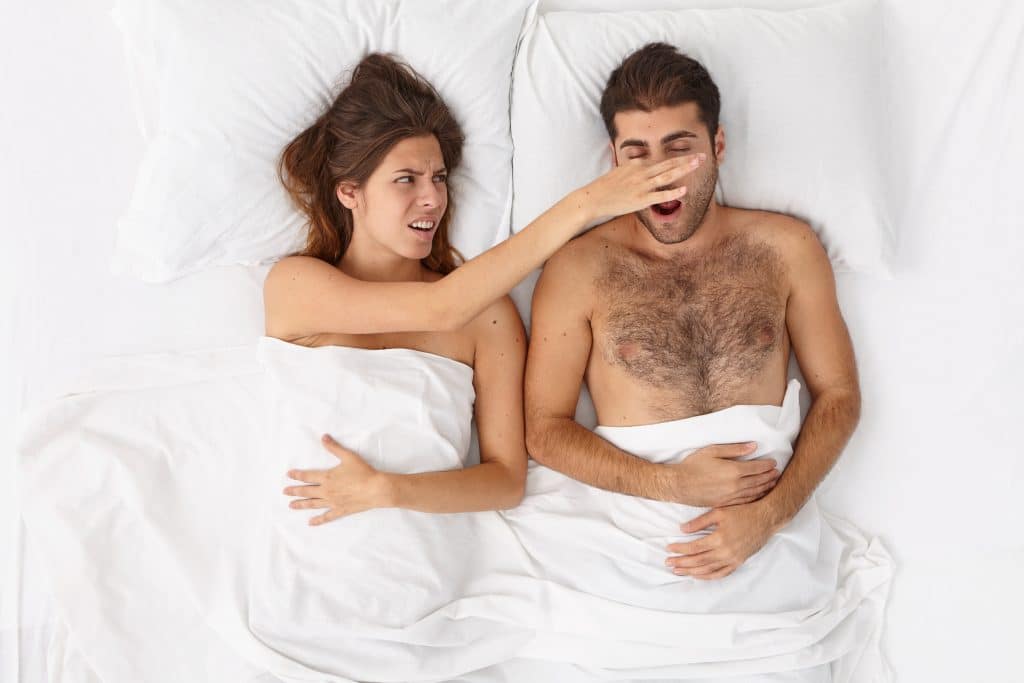 close up on couple lying in bed under white blanket scaled